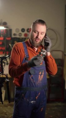Çekici tamircinin portresi bisiklet parçalarıyla atölyedeki müşteriye akıllı telefon araması yapıyor. Garaj iletişiminde çalışan bir adam. Boşluğu kopyala