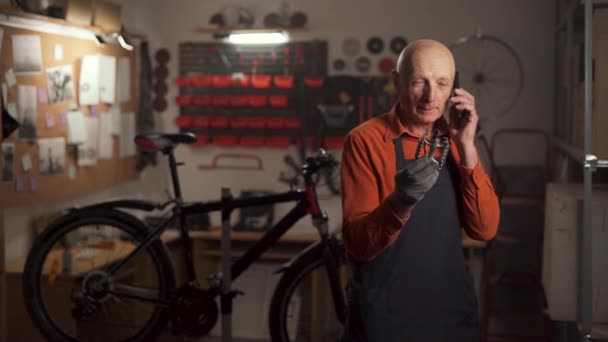 Зрелый Человек Чинит Велосипед Мастерской Звонит Мобильному Телефону Педалью Руке Стоковое Видео