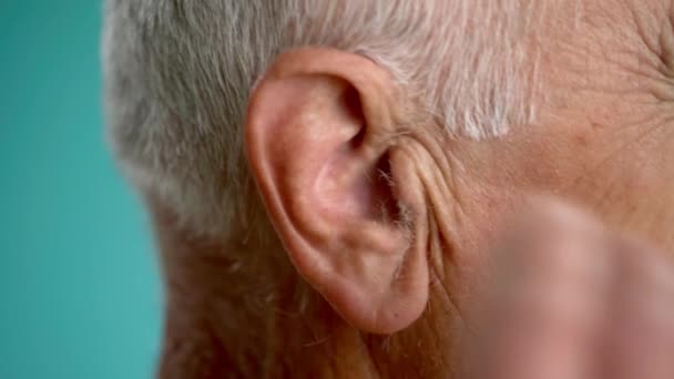 ヘッドフォンを耳に入れた老人のクローズアップ サイドビュー — ストック動画