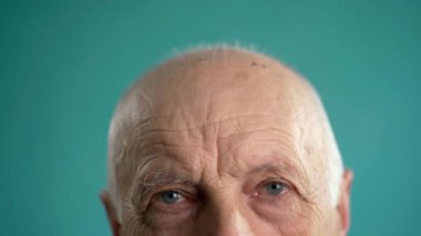 Mavi arka planda dalgın, olgun bir adam elleriyle alnına dokunurken endişeli görünüyor. Boşluğu kopyala