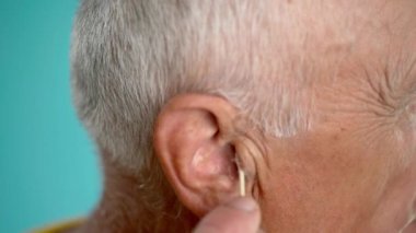 Yaşlı adamın pamuklu çubukla kirli kulakları temizlediği yakın plan. Kulak temizleme ve bakım konsepti