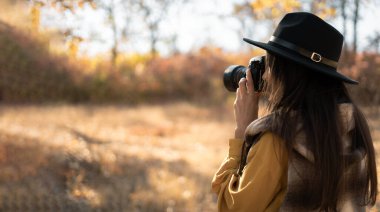 Sonbahar fotoğrafı çeken şapkalı bir kadın fotoğrafçı. Seyahat ve hobi konsepti. Boşluğu kopyala