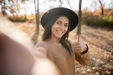 Sonbahar parkında yeşillik önünde selfie çeken İspanyol kadının portresi. Boşluğu kopyala