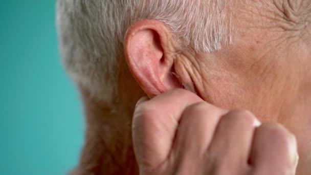 Old Man Massaging Earlobe While Standing Blue Background Close — Stock Video