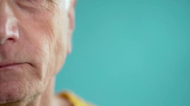 Mavi arka planda sakız çiğneyen yaşlı bir adamın yakın çekimi. Vücut parçaları konsepti. Boşluğu kopyala