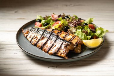 Restoranda ızgara uskumru fileto, sebze ve limon ile mavi tabakta. Boşluğu kopyala