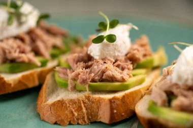 Konserve ton balıklı sandviç ve mavi tabakta avokado. Üst Manzara. Yemek tarifi geçmişi. Boşluğu kopyala