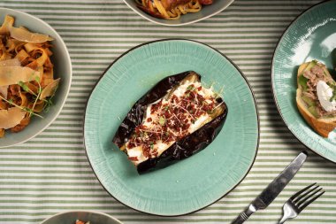 Peynirli fırında patlıcan. Vejetaryen yemek tarifi konsepti. Yemek tabakları olan masa manzarası.