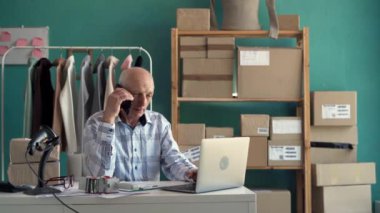 Satıcı yaşlı adam dizüstü bilgisayarda çalışıyor ve KOBİ online mağazasındaki ana ofisteki müşterileri arıyor. Boşluğu kopyala