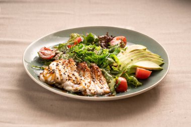 Sebze ve unagi sosuyla servis edilen bir tabakta yılan balığı ve avokado dilimleri. Deniz ürünleri salatası.