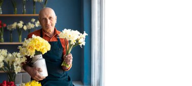 Yaşlı, açık tenli bir adam elinde kocaman buketler tutuyor. Alıcının seçimi için teklif