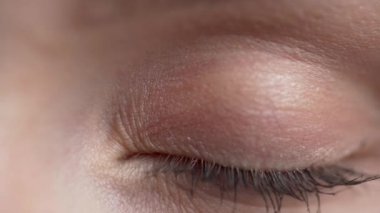 Genç bir kadının yüzüne yakın çekim. Şirin kız güzel mavi gözlerini açıyor. Mavi göz kameraya bakıyor. Yavaş çekim