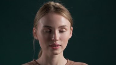 Genç sarışın kız uzun güzel saçlarını, saç bakımını ve saç modelini göstermek için at kuyruğunu ayırıyor. Koyu arkaplanda