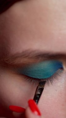 Profesyonel bir makyaj sanatçısı, modelin gözlerinin ifade ediciliğini vurgulamak için üst göz kapağının mukoza zarını çizmek için koyu gölgeli bir fırça kullanır. Aydınlık akşamın süreci