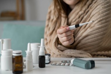 Kadın El Tutma Termometresi 'nin yakın çekimi, Evde Sıcaklık Kontrolü. Hastalık Zamanındaki Ateşi ve Sağlığı İzleyen Kadın, Sıcak Ev Ayarlarında Termometre Okumaya Odaklan