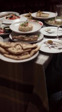 Sofrada şarap kadehi bulunan çeşitli yemekler sofistike bir yemek deneyimi için zemin hazırlıyor. Dikey video