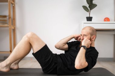 Spor adamı evde kıtır kıtır egzersiz yapıyor. Erkek, spor salonunda karın kası egzersizi yapıyor. Boşluğu kopyala