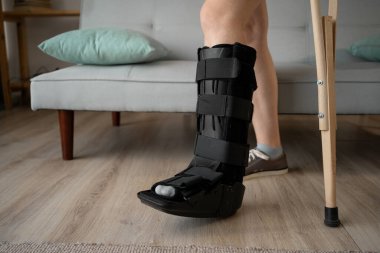 Bandajlı kadın koltuk değnekleriyle yürüyor. Ayak bileği yaralanması. Boşluğu kopyala