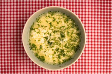 İtalyan stracciatella yumurtası çorbası. Masa örtüsü arka planında maydanozlu, üst manzaralı. Boşluğu kopyala