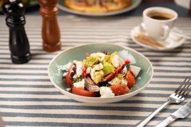 Avokado ve beyaz peynirli taze sebze salatası kahvaltıda bir kafede çatal bıçakla servis ediliyor. Sağlıklı kahvaltı ve diyet konsepti