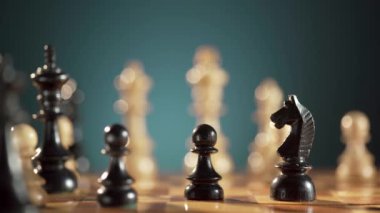Stratejik bir satranç hamlesinin yakın plan çekimi, tahtanın üzerine siyah satranç taşları yerleştiriliyor..