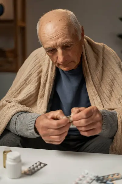 stock image elderly man takes pills from blister. Flu and cold treatment concept. copy space