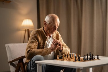 Geceleri rahat bir odada tek başına satranç oynayan yaşlı bir adam. Boşluğu kopyala