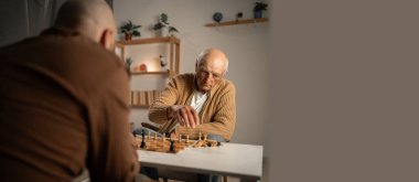 Yaşlı bir adam bir arkadaşıyla satranç oynamaktan hoşlanır, arkadaşlığın ve stratejik oyunların neşesini vurgular..