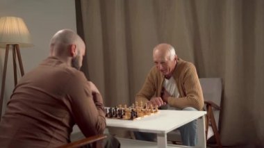 Evde, yaşlı bir adam ve genç bir adam bir satranç oyunu sırasında birbirlerine bağlanırlar, ilişkilerini güçlendirmek için stratejiyi kullanırlar.