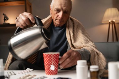 Yaşlı bir adam kanepeye oturur, battaniyeye sarınır çay yapmak için çaydanlıktan sıcak su döker. Önündeki masada çeşitli ilaçlar var. Hastalığını evde tek başına tedavi ediyorlar..