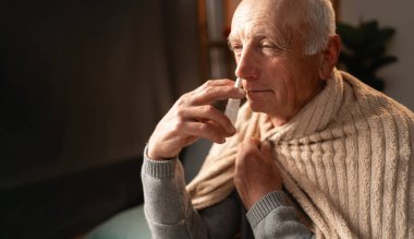 Evde burun spreyi kullanarak grip ve soğuk algınlığı geçiren yaşlı, olgun, hasta bir adam. rhinitis, ilaç ve sağlık hizmeti kavramı