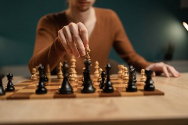 Evde satranç oynayan genç adama yakın çekim, şövalye hamlesi. Seçici odak