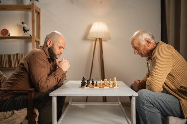 Yaşlı bir adam ve genç bir adam evde satranç oynuyorlar. Her ikisi de stratejik düşünmeyi ve rahat bir ortamda nesiller arası bağ kurmayı vurgulayarak oyuna derinden odaklanmış durumda..