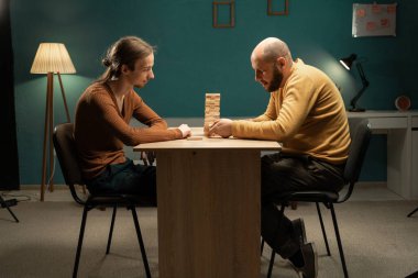 Arkadaşlar tahta bloklarla oyun oynuyorlar, evde masada strateji oyunu oynuyorlar. Hobi ve ev hayatı kavramı