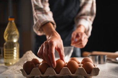 Evde pişirme malzemeleri hazırlarken kadın eller kartondan yumurta topluyor. Ev yapımı konsept.