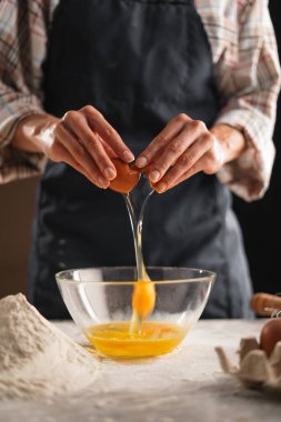 Yüzü olmayan kadın ellerine yakın plan bir kaseye yumurta atar, kabukları elinde tutar..