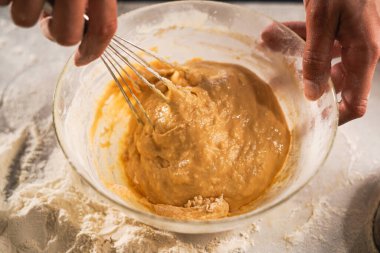 Hamur işi şefi çırpıcıdan hamur yapıyor. Kırsal ahşap masada malzemelerle waffle pişirmek. El yapımı tatlı ve pişirme süreci konsepti