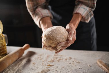 Kadın elleri fırına koymadan önce parayı masanın üstünde tutuyor. Yakın plan.