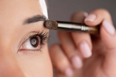 Makyöz kadın gözüne göz farı sürüyor. Makyaj malzemesi. Göz farı. Yakın plan.