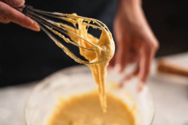 Kadın aşçı kek hamurunu metal çırpıcıyla karıştırıyor. Ev yapımı konsept. Yakın plan.