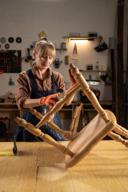 Yaşlı bir kadın atölyesindeki eski ahşap sandalyeyi titizlikle restore ediyor, eski verniği çıkarmak için yıpratıcı bir sünger kullanıyor. Antika mobilya tamiri ve işçiliğine odaklan