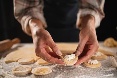 Ev yapımı hamur köftelerini un kaplı bir yüzeyde süzme peynirle ustalıkla hazırlarken yakın plan çekimler. Resim geleneksel pişirme sürecini yakalar, boşluğu kopyalar