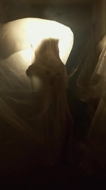 Şeffaf filme sarılmış bir kadın, nefes almasını engelleyen duyguların ve ezici düşüncelerin akışını sembolize ederek kendini özgür bırakmaya çalışır. Işık ve gölge sahnenin dramını arttırır.