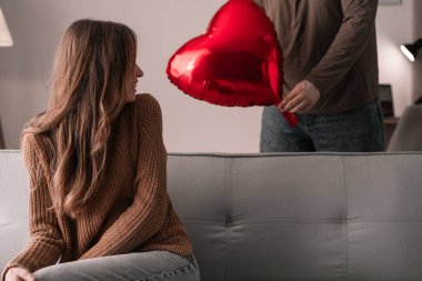 Sevgililer günün kutlu olsun. Aşık bir adam, 14 Şubat 'ta sevgililer gününü evde kutlayan genç karısına kalp şeklinde balon veriyor. Boşluğu kopyala