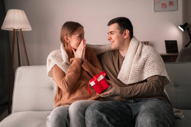 Sevgililer Günü 'nü evde kutlayan genç bir çift. Erkek arkadaşı ona sürpriz hediye verirken mutlu kadın şoka uğradı. Gülümseyen adam sevgili kız arkadaşına hediye hazırlıyor. Boşluğu kopyala