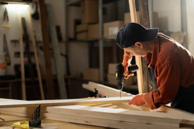 Bayan Carpenter atölyesinde çalışarak kereste bloğuna delik açıyor. Stüdyoda mobilya montajı yapan bir kadın. Elektrikli matkap kullanan ahşap ustası. Boşluğu kopyala