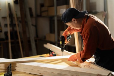 Bayan Carpenter atölyesinde çalışarak kereste bloğuna delik açıyor. Stüdyoda mobilya montajı yapan bir kadın. Elektrikli matkap kullanan ahşap ustası. Boşluğu kopyala