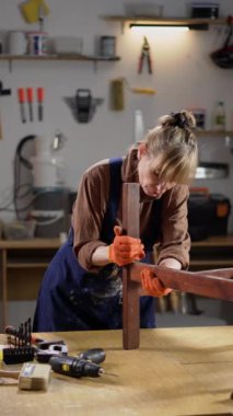 Üst düzey bir kadın atölyesinde eski bir ahşap sandalyeyi restore ediyor. Döşeme yeni kumaşla döşenmiş. Mobilya restorasyonu ve küçük işletme girişimciliği kavramı