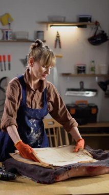 Bir kadın atölyesinde antika bir sandalyeyi restore ediyor, eski döşemeleri kaldırıyor, mobilya restorasyonunda küçük işletme girişimciliği yapıyor.