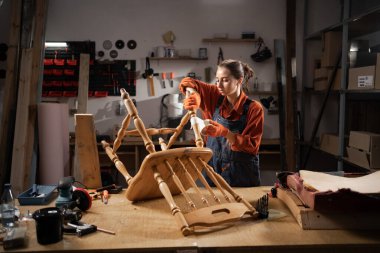 Atölyede boyamak için eski tahta sandalyeye yapışkan bant yapıştıran çekici bir kadın. Mobilya tamir, onarım ve onarım konsepti